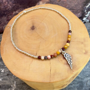 pulsera elasticada con medalla diseño alita hecha de plata 950, mostacillas de plata 1000 y piedras jaspe mokaita