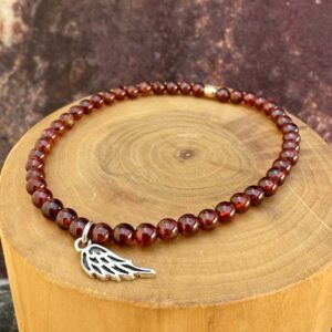 pulsera elasticada con medalla diseño alita hecha de plata 950 con mostacillas de piedras granate