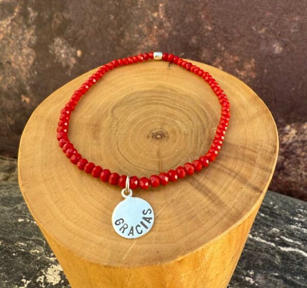 pulsera elasticada con medalla diseño gracias hecha de plata 950 con mostacillas de cristal rojo