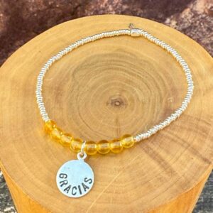 pulsera elasticada con medalla diseño gracias hecha de plata 950, mostacillas de plata 1000 y piedras citrino