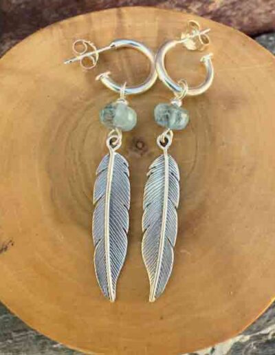 Aros de plata pura con dije de argollas y plumas acompañado de piedra aguamarina