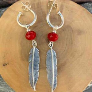 Aros de plata pura con dije de argollas y plumas acompañado de piedra cristal rojo