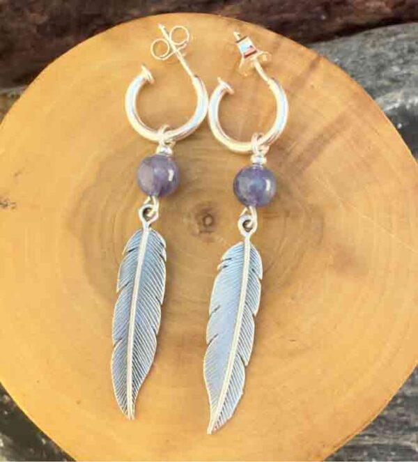 Aros de plata pura con dije de argollas y plumas acompañado de piedra tanzanita.