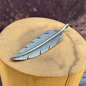 medalla hecha de plata 950 con diseño de pluma grande puntuda.