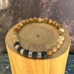 Pulsera elasticada formada con mostacillas de cobre con texturas de lineas martilladas. acompañado de mostacillas de piedra volcanica y jaspe amarillo