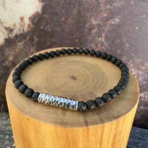 Pulsera elasticada formada con un tubo central de plata martillada acompañado de mostacillas de piedra volcanica.