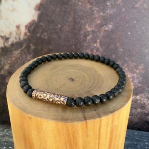 Pulsera elasticada formada con un tubo central de cobre martillado, acompañado de mostacillas de 4 milímetros de diámetro de piedra volcanica negra