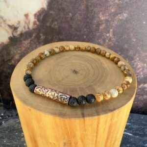 Pulsera elasticada formada con un tubo central de cobre martillado, acompañado de mostacillas de 4 milímetros de diámetro de piedra volcanica negra y jaspe amarillo