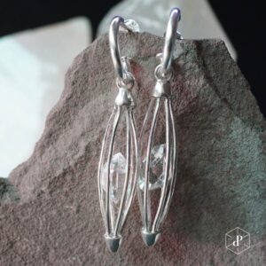 aros con diseño de jaula ovalada hecha de p´lata 950 que dentro sostiene un cuarzo diamante herkimer de 5 centimetros