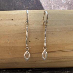 Aros tipo argolla con una ojiva colgante hecha de plata 950 que contiene una piedra herkimer de 2 centimetros de diámetro. Ésta cuelga desde los aros por unas mostacillas de plata 1000.