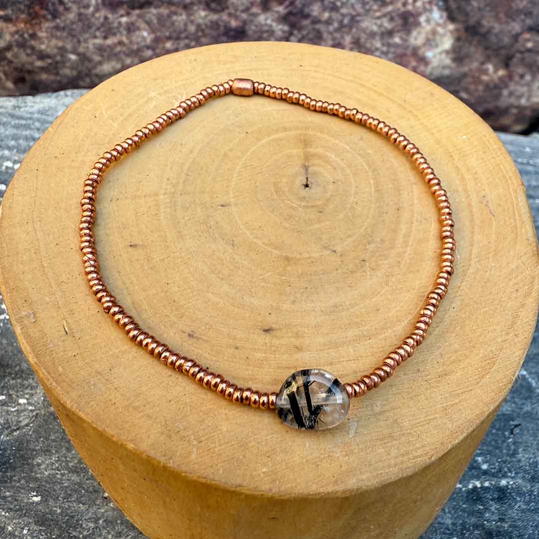 pulsera elasticada con mostacillas de cobre, con una piedra central de cuarzo rutilado