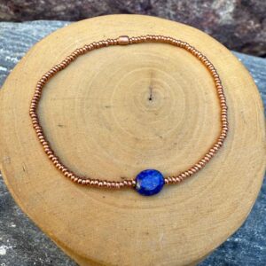 pulsera elasticada con mostacillas de cobre, con una piedra central de lapislazuli