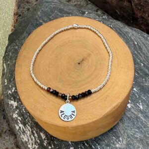 pulsera elasticada con mostacillas de onix y plata 1000, con medalla circular con la palabra alegria grabada, hecha de plata 950