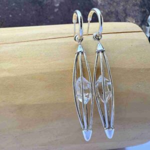 aros con diseño de jaula ovalada hecha de p´lata 950 que dentro sostiene un cuarzo diamante herkimer de 5 centimetros